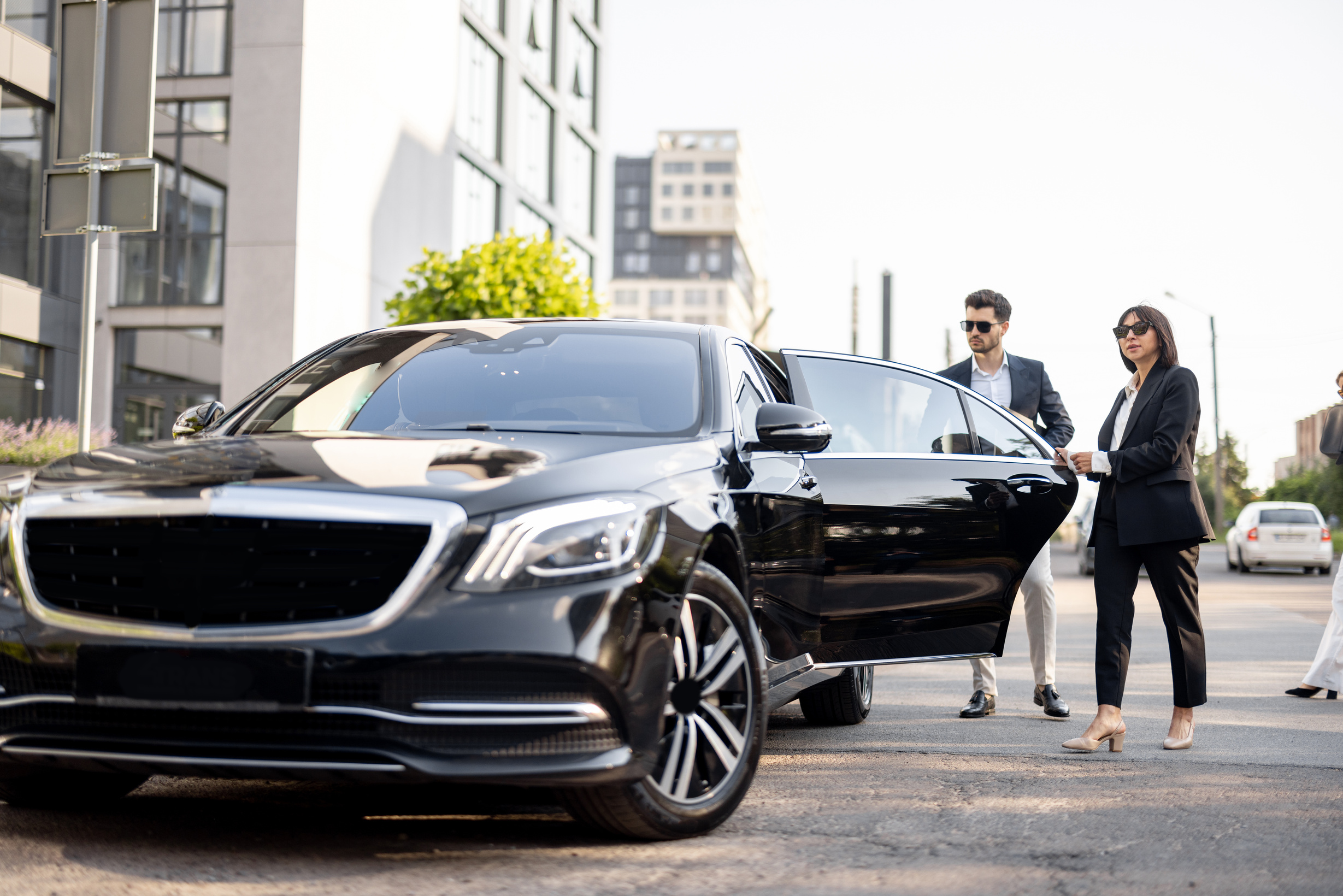 Female Chauffeur Helping a Businessman to Get inside the Car