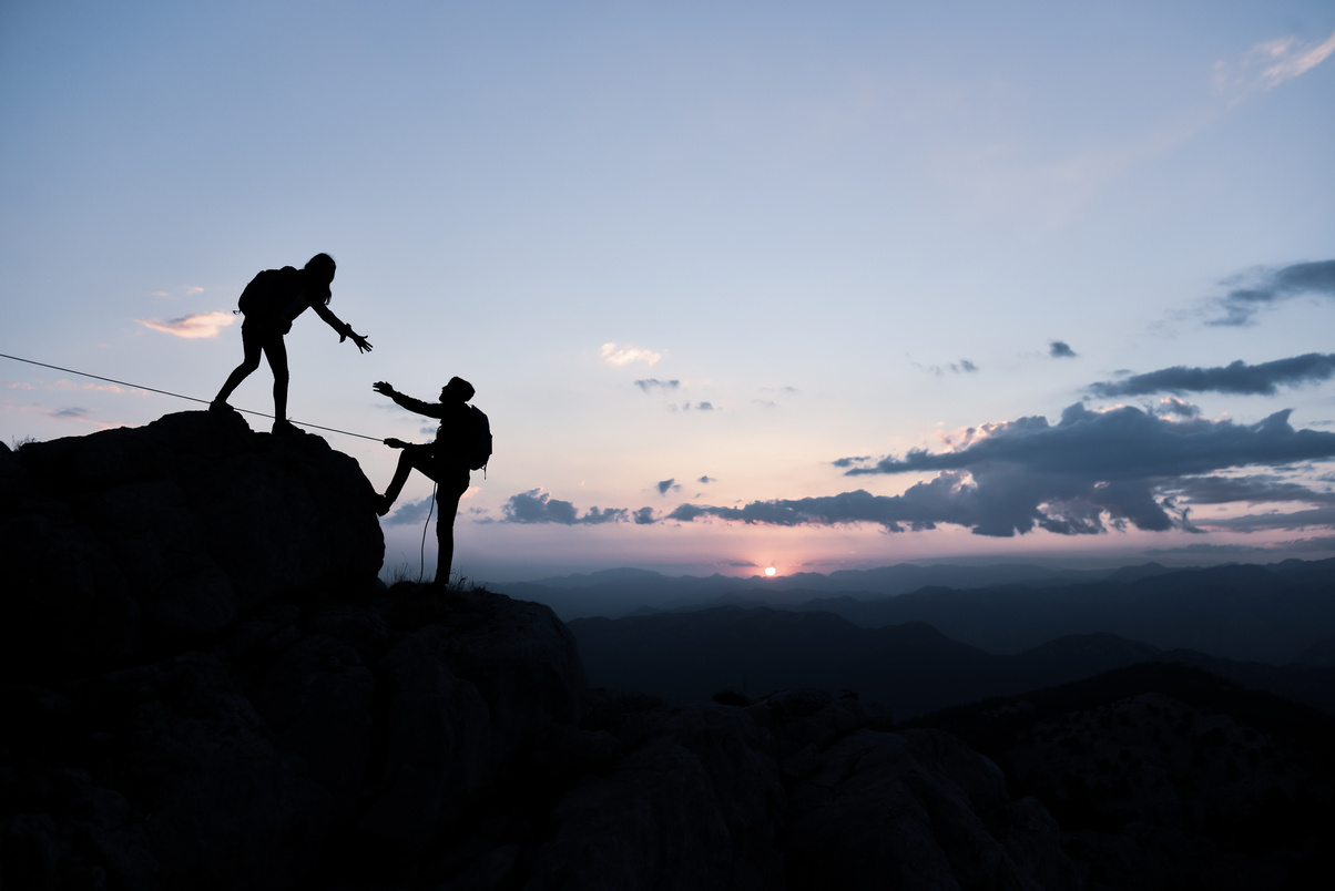 two climbers, one helping the other up, showcasing the support we provide to travellers